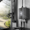 Irrigation system with controller and nozzles attached to a wall near a window with a view of greenery.