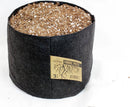 Black fabric pot with soil and a label on a white background